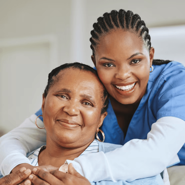 A caregiver embracing an elderly woman she cares for, both smiling