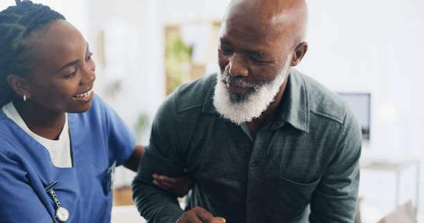 A caregiver smiling and assisting an elderly man at home